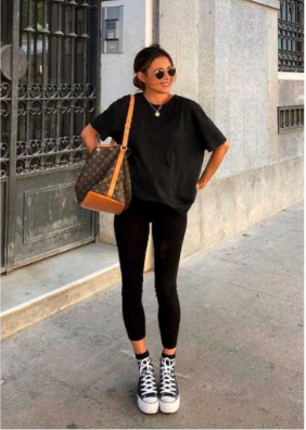 A girl with a black t-shirt on with leggings and sneakers on.