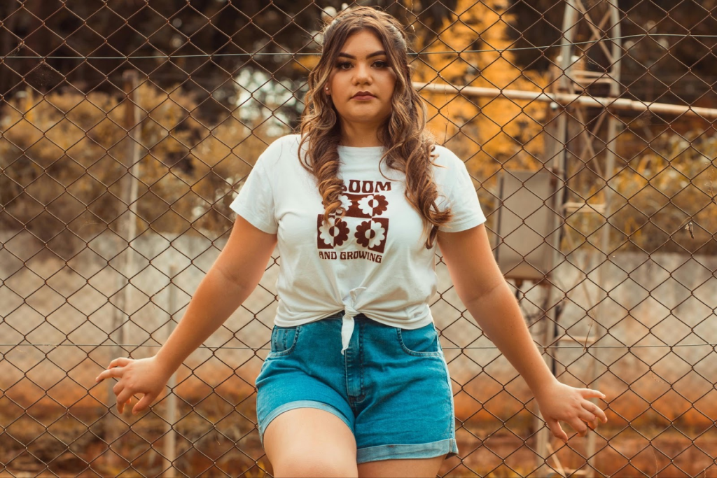 A girl wearing a graphic tee tied in a not at the bottom with a pair of denim shorts.